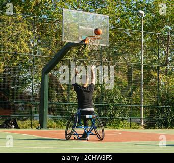 Jeune homme beau en fauteuil roulant jouant au basket-ball Banque D'Images