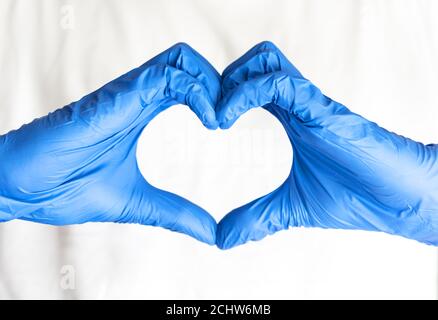 Médecin en gants chirurgicaux bleus faisant le coeur avec les mains Banque D'Images