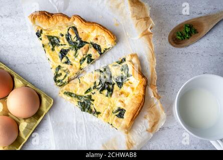 Tranches de quiche fourrées de poulet, verger avec une cuillère en bois sur fond doux Banque D'Images