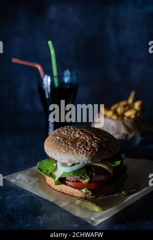 hamburger fait à la main avec frites et coke avec pailles à l'obscurité arrière-plan Banque D'Images