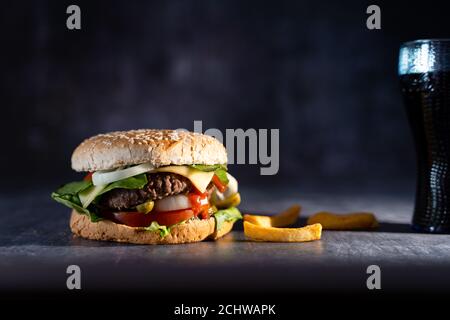 hamburger fait à la main avec frites et sur fond sombre Banque D'Images