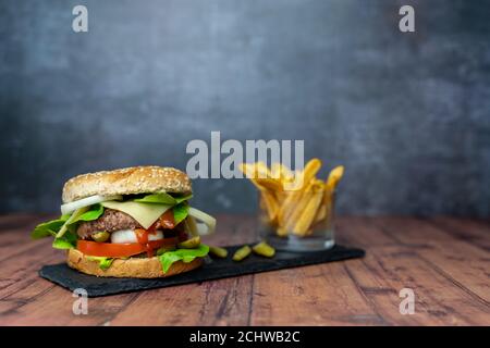 hamburger fait à la main avec frites et sur fond sombre Banque D'Images