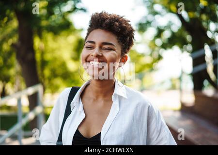 Photo d'une femme africaine souriante et heureuse qui marche à l'extérieur stationnement Banque D'Images