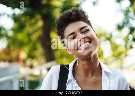 Photo d'une femme africaine souriante et heureuse qui marche à l'extérieur stationnement Banque D'Images