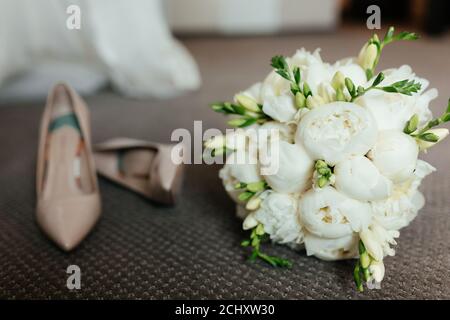 Bouquet de mariage de pivoines et talons de mariée beige. Matin de la mariée Banque D'Images