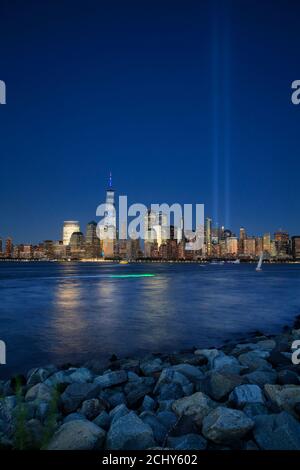 Vue nocturne sur les gratte-ciel de Lower Manhattan avec une vue annuelle de 9/11 Des lumières en hommage projetées dans le ciel avec le fleuve Hudson en premier plan Depuis Liberty State Park.New Jersey.USA Banque D'Images