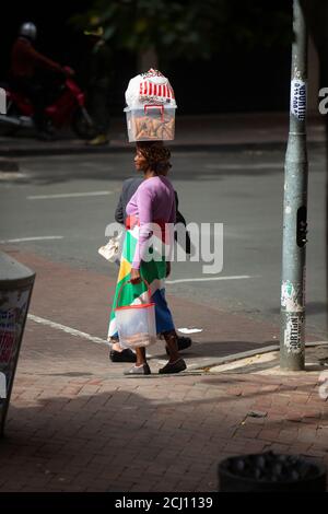 Femme africaine enveloppée dans le drapeau sud-africain, portant des provisions sur la tête. Johannesburg, Afrique du Sud Banque D'Images