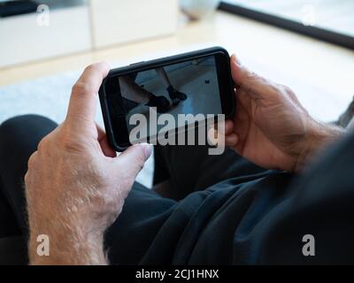 Homme regardant une vidéo YouTube sur le téléphone (iPhone) avec un artisan pose de carreaux de céramique émaillée Banque D'Images