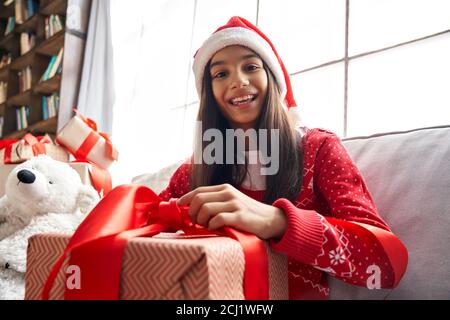 Joyeux indien latin enfant fille ouverture Noël cadeau vidéo appel famille, vue webcam. Banque D'Images