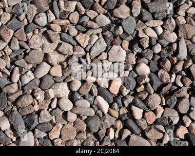 Arrière-plan texturé de pierres naturelles. Petites pierres colorées baignées de lumière du soleil. Banque D'Images