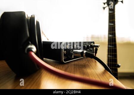 Casque et son sur la table et une guitare basse sur l'arrière-plan. Banque D'Images