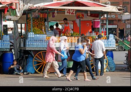 Un stand de fruits et de jus est passé par les gens pendant la journée dans le vieux marché médina de Marrakech, au Maroc. Banque D'Images