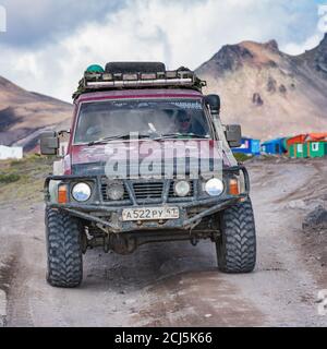 Vieux véhicules à quatre roues motrices Nissan Patrol roulant sur la route rocheuse de montagne sur fond volcanique. Expédition dans les destinations de voyage Banque D'Images