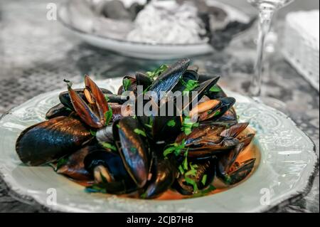 Assiette antique avec moules dans une sauce crémeuse à l'ail sur la table dans un restaurant. Plats de fruits de mer au restaurant Banque D'Images