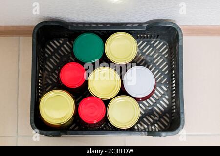 vue de dessus des conserves d'hiver - bocaux de légumes marinés et fruits dans une boîte en plastique sur le sol Banque D'Images