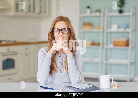 Femme positive regardant la caméra et écoutant quelqu'un pendant vidéocall ou téléconférence en ligne Banque D'Images