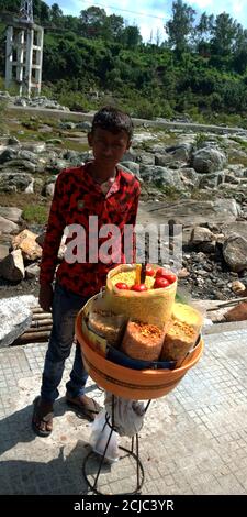 DISTRICT DE JABALPUR, INDE - 17 AOÛT 2019 : petit garçon asiatique pauvre vendant des collations à la rue de la rivière Narmada. Banque D'Images