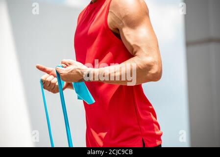 S'adapter musclé sport homme faisant l'exercice biceps curl avec la résistance bande en plein air Banque D'Images