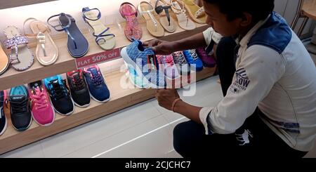 DISTRICT KATNI, INDE - 17 SEPTEMBRE 2019 : un garçon indien à la recherche de chaussures dans une salle d'exposition. Banque D'Images