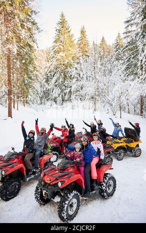 Yaremche, Ukraine - 02 février 2020 : groupe de personnes gaies assis sur des VTT à quatre roues, profitant d'une belle journée d'hiver dans des montagnes enneigées, incroyable épinettes enneigées sur fond. Banque D'Images