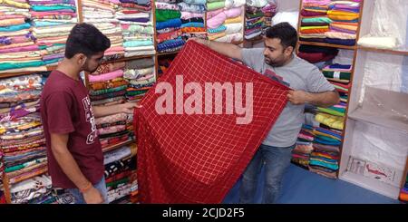 DISTRICT KATNI, INDE - 18 SEPTEMBRE 2019 : un vendeur indien affiche le saari traditionnel dans un magasin de vêtements pendant le marché indien des festivals offre la vente. Banque D'Images