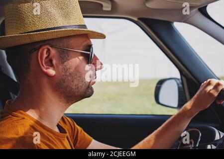 Jeune homme beau en voiture avec chapeau de paille Banque D'Images
