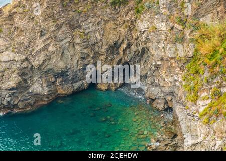 Superbe vue rapprochée de la petite crique près de la marina de Corniglia. Un couple en équipement de bain tente d'atteindre la baie rocheuse avec sa belle... Banque D'Images