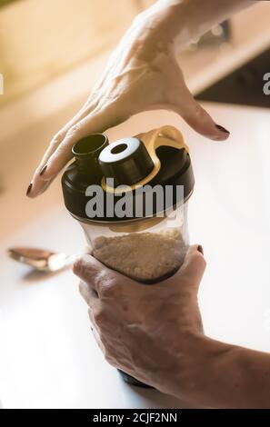 les mains de fille avec le vitiligo faisant un shake de protéine après le sport Banque D'Images