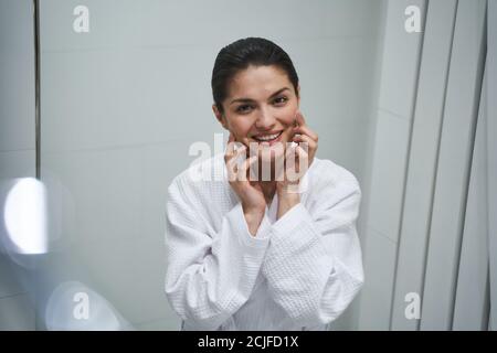 Femme souriante frottant une crème pour le visage sur sa peau Banque D'Images