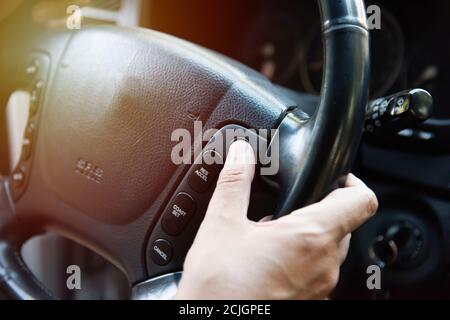 Gros plan d'un homme qui a mis le régulateur de vitesse en fonction le volant de direction Banque D'Images