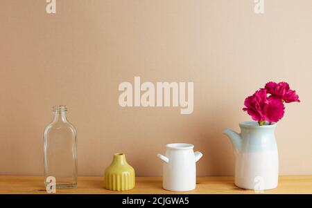 Fleurs de carnation en spray roses dans un vase sur une table en bois avec fond beige. Arrangement floral, espace de copie Banque D'Images