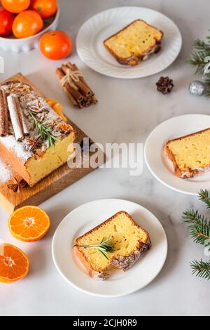 Boulangerie d'hiver. Gâteau aux agrumes décoré de mandarines, de romarin, d'épices et de sucre en poudre. Joyeux Noël et bonne année concept. Banque D'Images