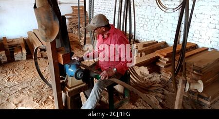 DISTRICT KATNI, INDE - 16 SEPTEMBRE 2019 : le forgeron indien affûte la lame de coupe du bois à l'atelier. Banque D'Images