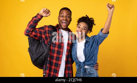 Joyeux couple africain de touristes secouant les Fists sur fond jaune Banque D'Images