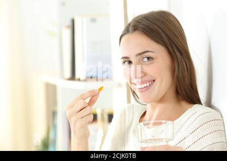 Bonne femme tenant une pilule de vitamine prête à le manger se tenir à la maison et regarder la caméra Banque D'Images