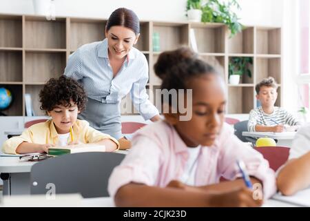 Accent sélectif de l'enseignant se tenant à côté des élèves multiculturels en classe Banque D'Images