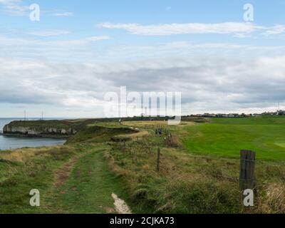 Marcheurs sur le sentier côtier à Flamborough Head East Riding Du Yorkshire Angleterre Royaume-Uni avec le phare dans la distance Banque D'Images