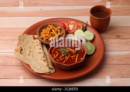 Dhaba style Sev bhaji/sabzi/curry fait en curry de tomate avec gathiya shev, servi avec chapati/ roti. Banque D'Images