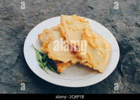 Tempe Mendoan est un type de plat de tempeh fait à partir de tempeh mince, et frit dans la farine pour qu'il ait un goût savoureux et croquant avec de la sauce soja dans une assiette en bois est Banque D'Images