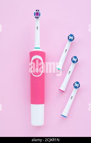 Brosse à dents électrique pour nettoyer les dents et la tête de brosse ronde sur fond rose. Buses bleues. Concept d'hygiène buccale Banque D'Images