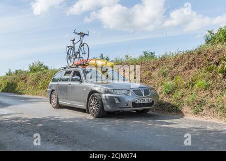 Voiture de domaine Rover avec kayak et porte-vélos avec vélo monté sur le toit à Cornwall. Pour les vacances à vélo, les amateurs de kayak, les promenades en Angleterre. Banque D'Images