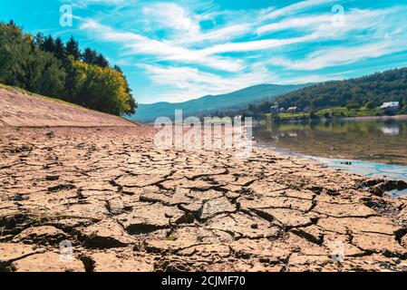 Sol sec fissuré sur le lieu d'arrosage de séchage, côte de rivière, beau paysage sur le fond. Banque D'Images