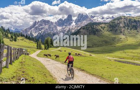 Belle et active femme senior à cheval son vélo électrique de montagne sur le haut plateau de Prato Piazzzo dans les trois pics Dolomites, silhouette rocheuse de Banque D'Images