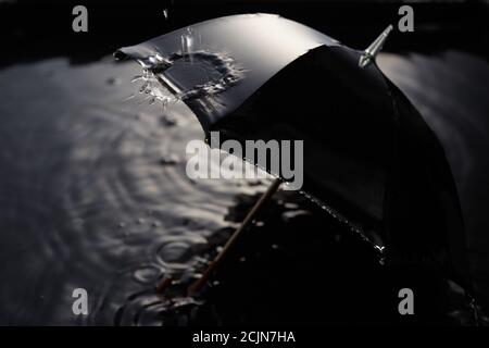 Gouttes de pluie tombant du parapluie noir. Concept de mauvais temps. Banque D'Images