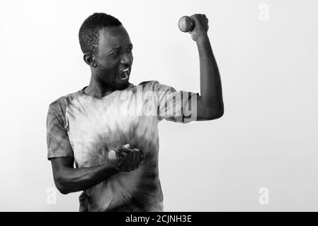 Jeune homme africain se sentant puissant tout en tenant des haltères légères et fléchir les muscles Banque D'Images