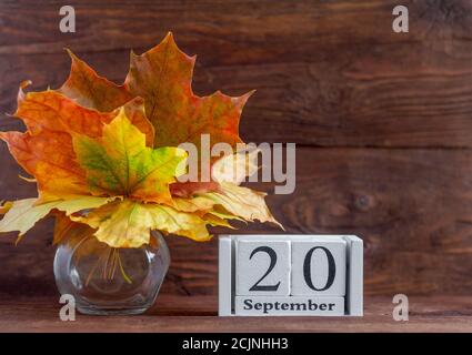 Septembre 20 sur un calendrier en bois et un bouquet d'automne de feuilles de couleur érable. Date du mois d'automne. Le concept de l'automne doré. Banque D'Images