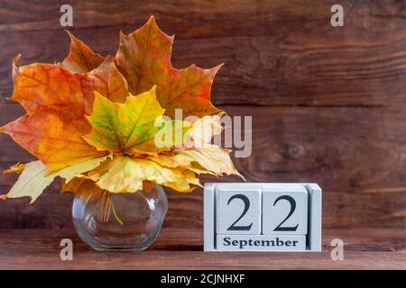 Septembre 22 sur un calendrier en bois et un bouquet d'automne de feuilles de couleur érable. Date du mois d'automne. Le concept de l'automne doré. Banque D'Images