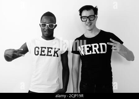 Photo en studio d'un jeune homme de Geek africain noir heureux avec Européen Nerd homme contre sourire et faire signe de paix Banque D'Images