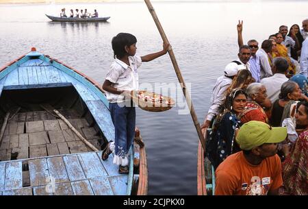 23.03.2010, Varanasi, Uttar Pradesh, Inde, Asie - UNE fille tente de vendre des fleurs aux passagers de bateau à un ghat sur la rive du fleuve Saint Ganges. Banque D'Images