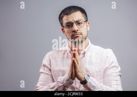 Portrait de l'homme agréable à prier pour la santé et d'affaires. isolé sur fond gris. S'il vous plaît, donnez-moi le travail. Je vous promets que je ne vais pas le faire encore une fois Banque D'Images